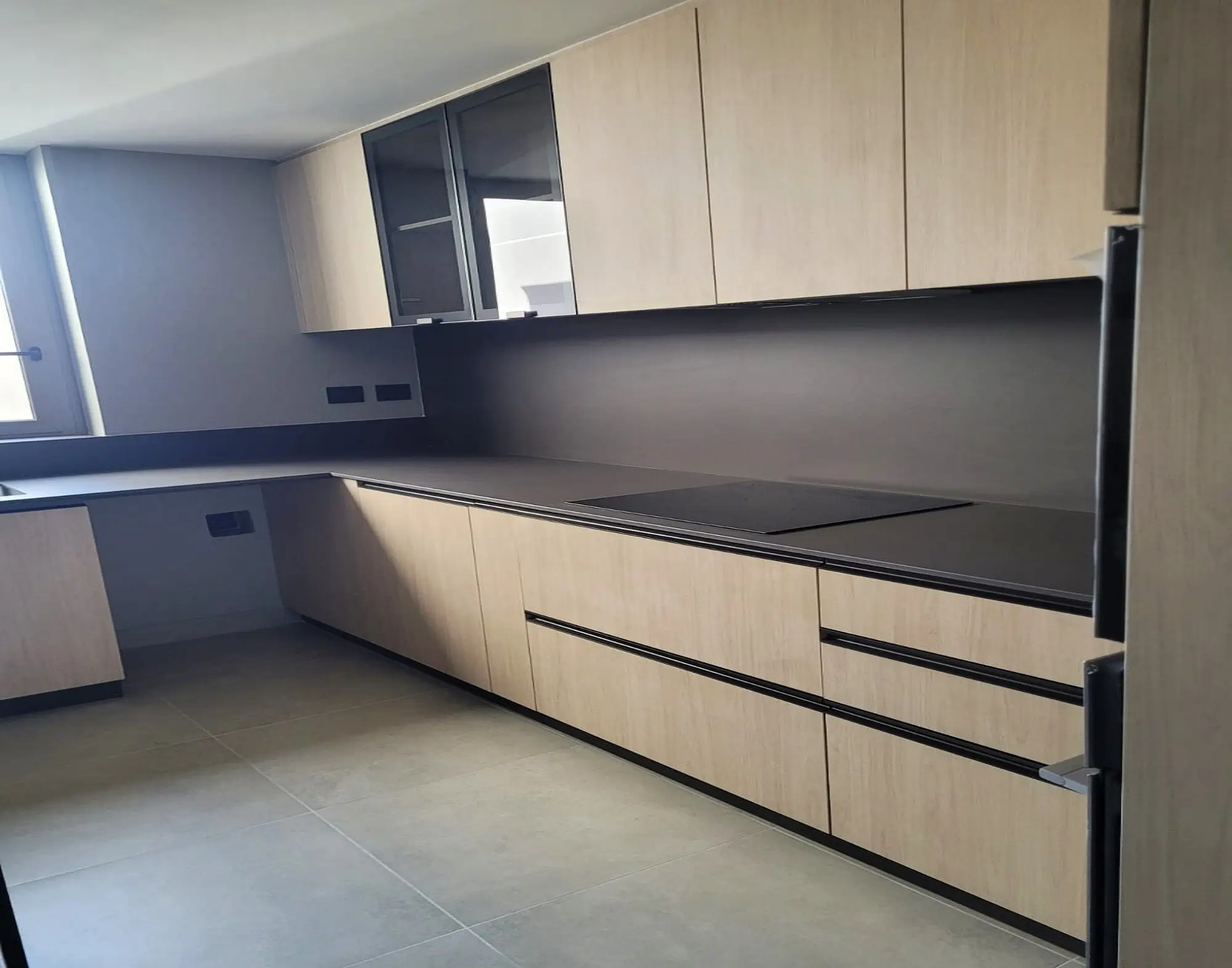 Cocina moderna con muebles en melamina madera clara, cubierta de cuarzo oscuro y electrodomésticos empotrados, diseño exclusivo de Style Muebles en Perú